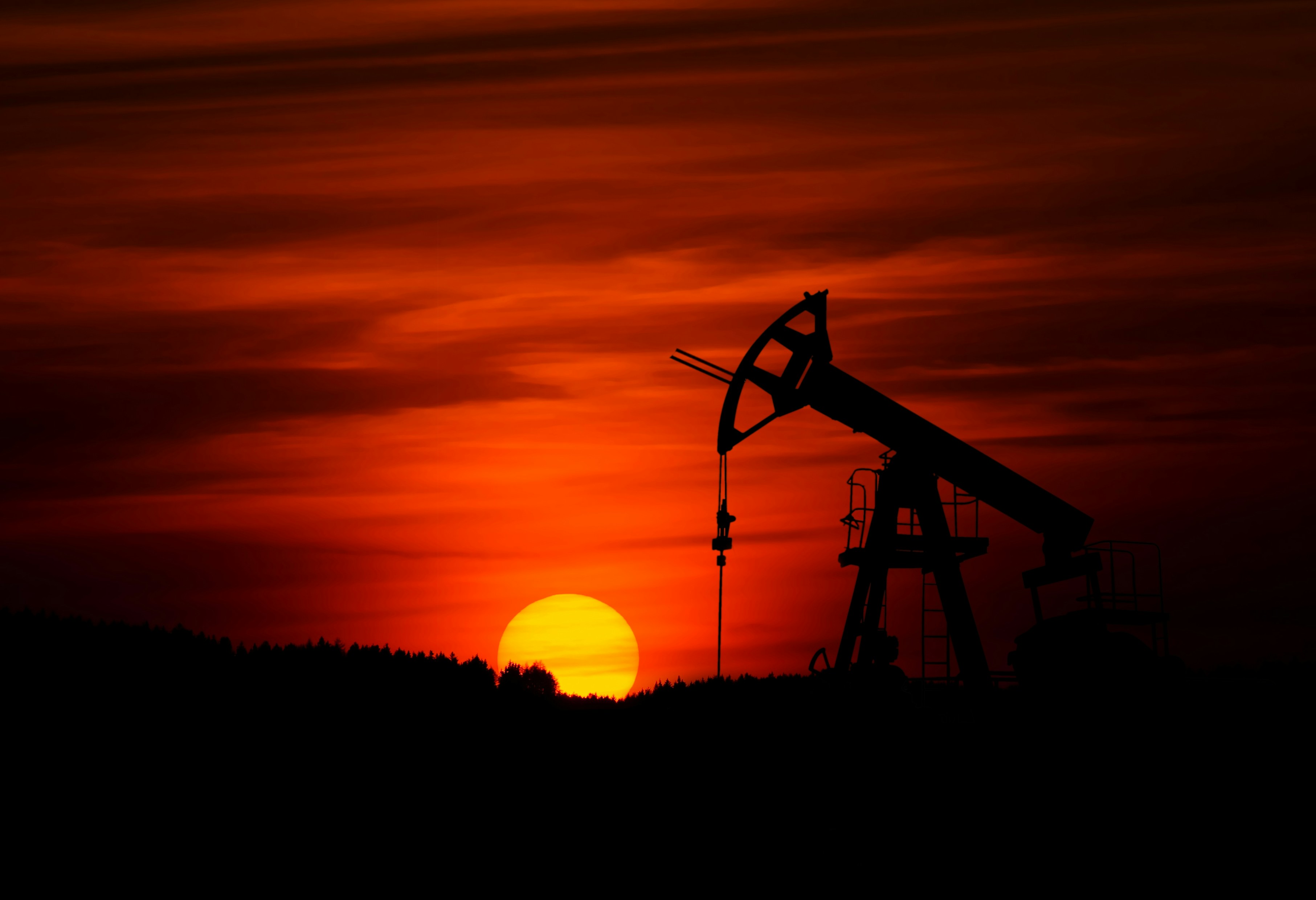 Oil pumpjack silhouette against dramatic sunset sky representing AquaSmart Oil & Gas operations
